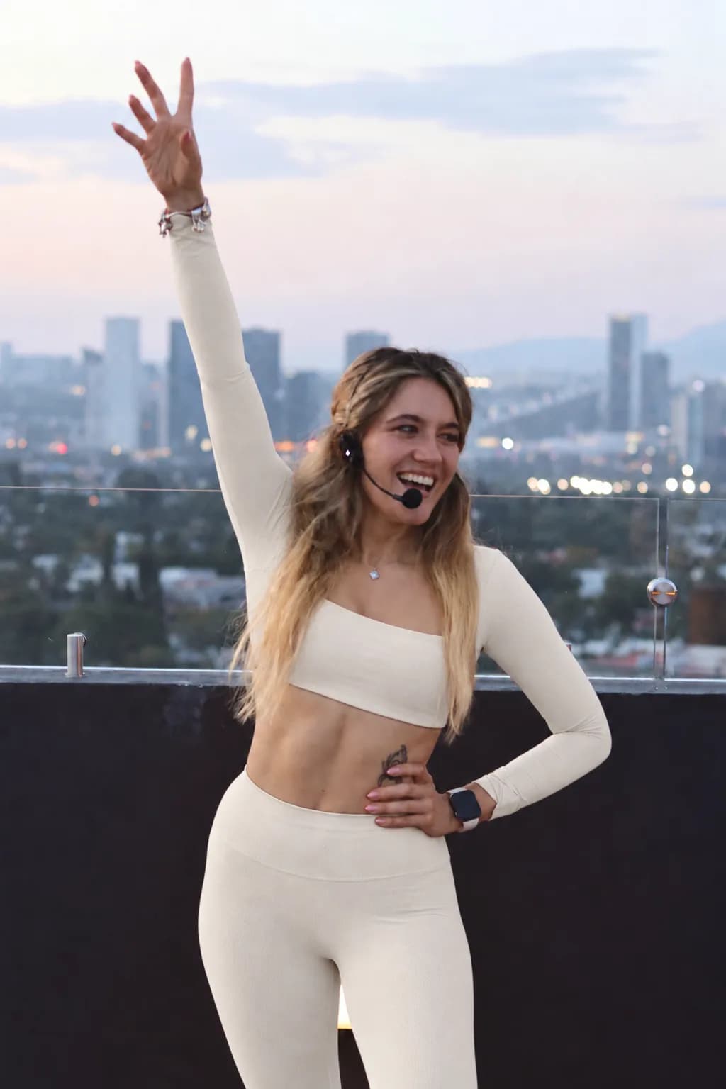 Luisa sonriendo con el brazo en alto durante una clase en una azotea al atardecer
